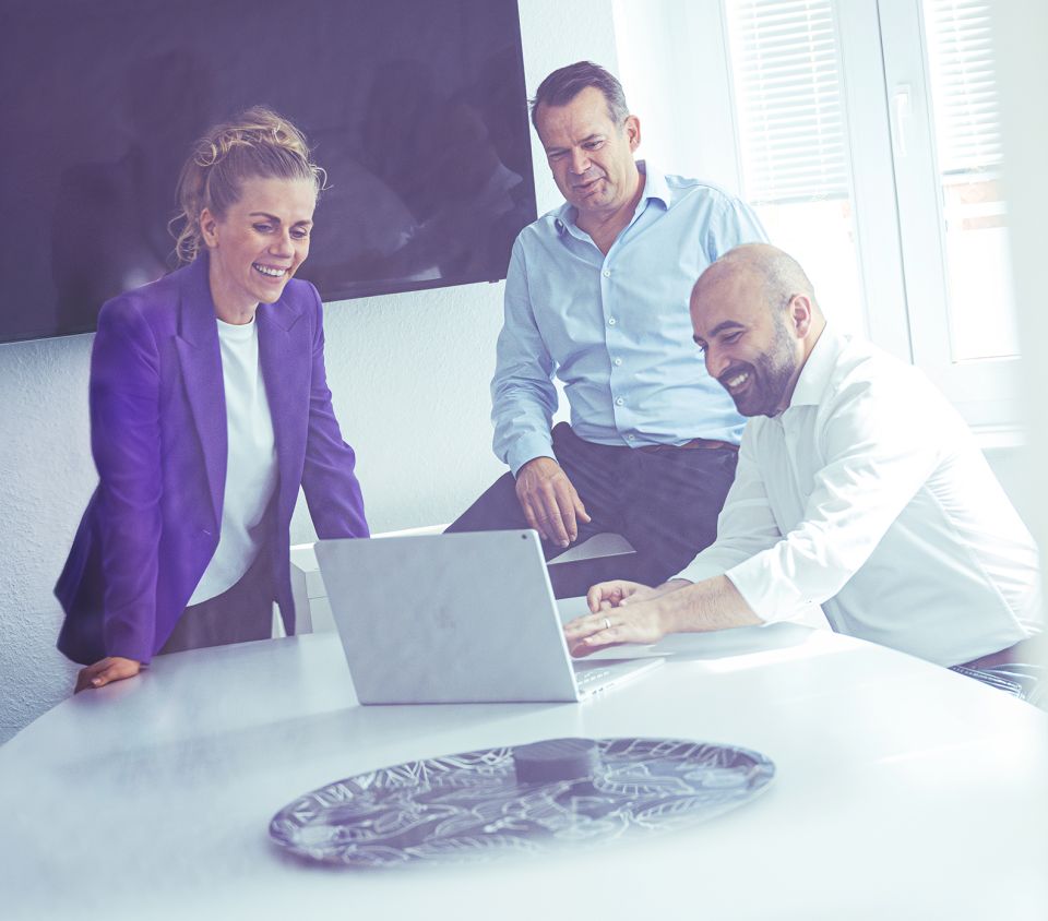 Drei Menschen besprechen etwas am Laptop