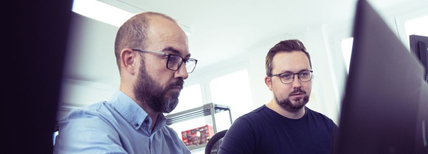 Zwei IT-Spezialisten arbeiten am Laptop